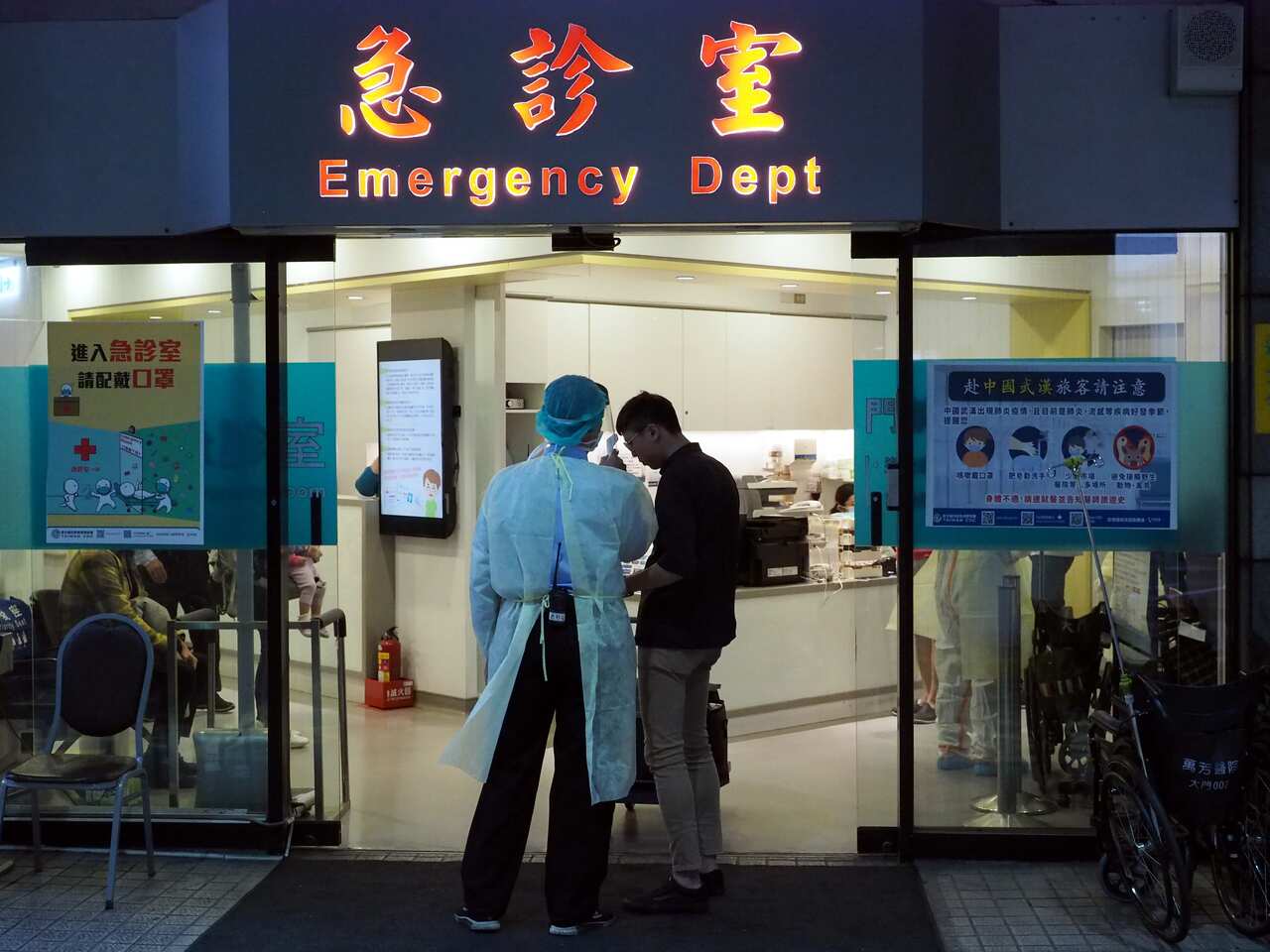 A medical staff member (L) waits to check the body temperature of those at risk at a hospital in Taipei, Taiwan.