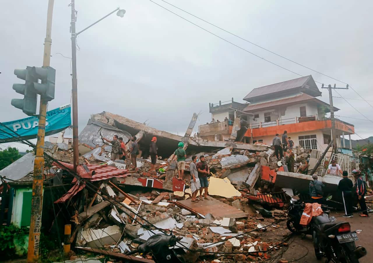 Residents inspect an earthquake-damaged buildings in Mamuju, West Sulawesi following the earthquake on 15 January, 2021. 