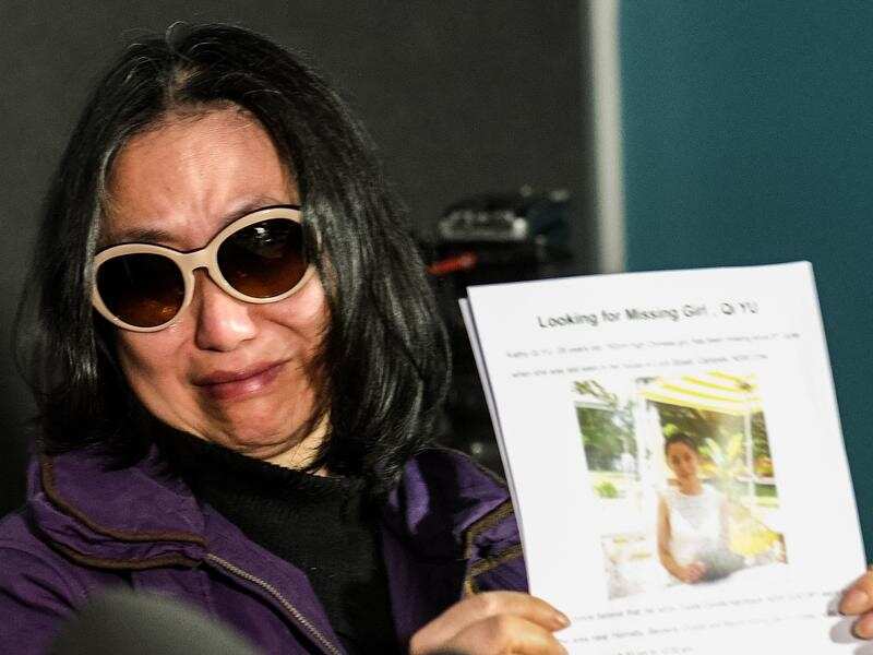 Qing He, the mother of missing women Qi Yu, with her photo.
