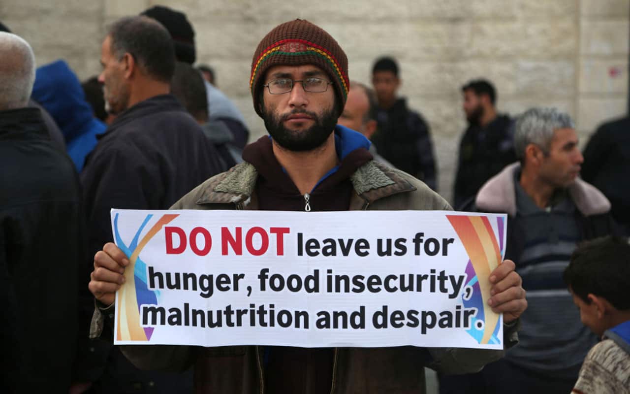 A Palestinian man hold banners against cutting off food aid during the protest outside the UN headquarters in Gaza City, Jan. 4, 2018,