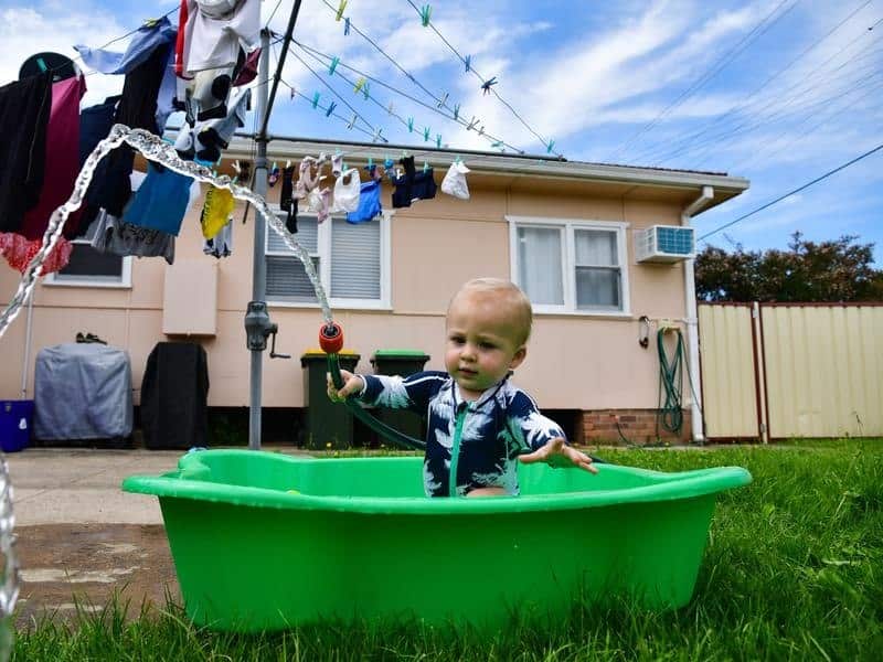 Harry Mayer, 1 of Lurnea plays with a garden hose