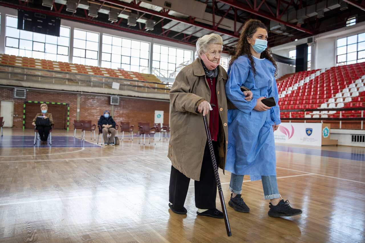 An elderly woman is being accompanied before receiving a dose of the AstraZeneca vaccine from Kosovo’s first COVAX supply as the nation begins its rollout for people aged over 85 on 8 April.