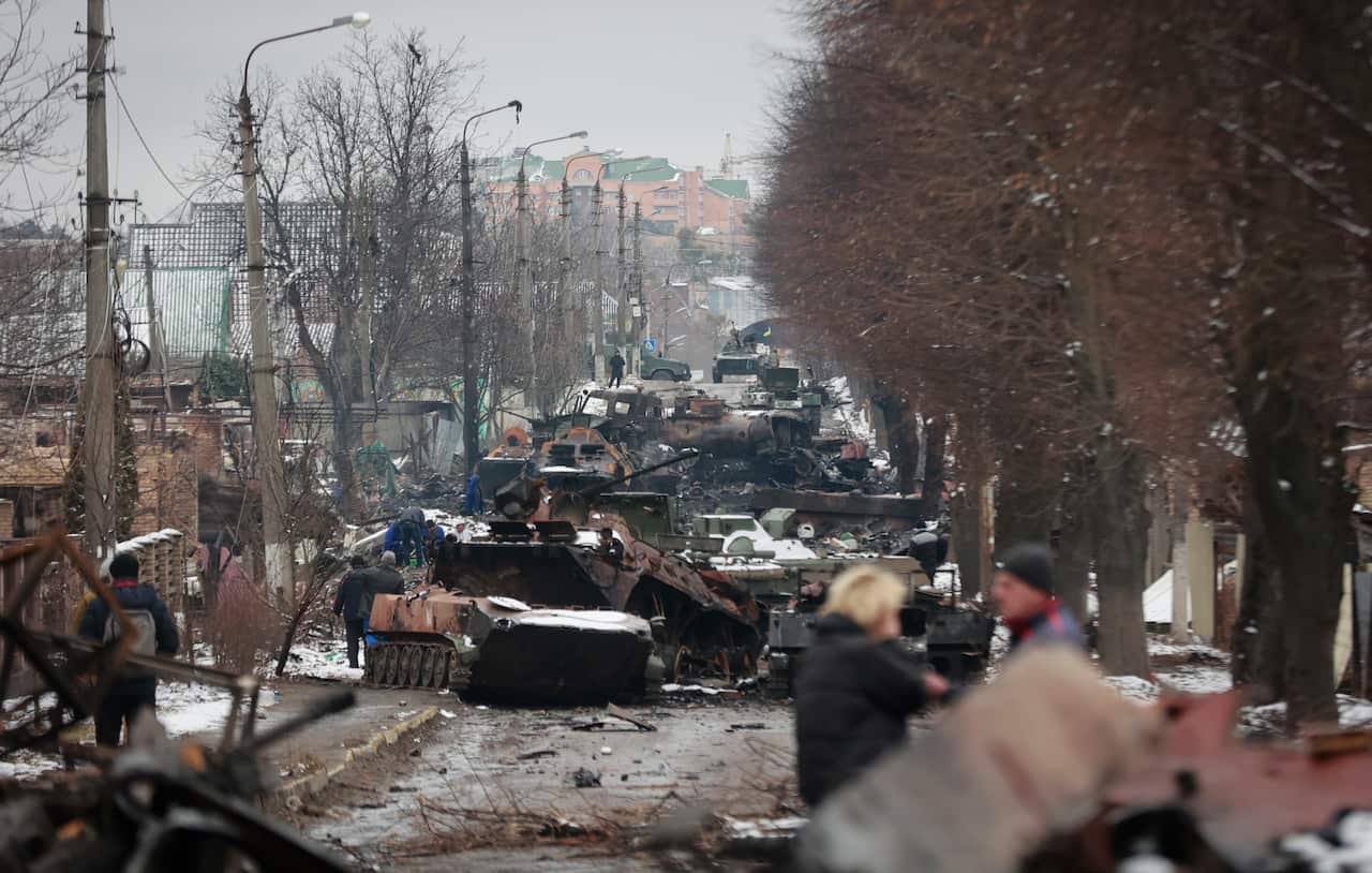 People look at the gutted remains of Russian military vehicles on a road in the town of Bucha, close to the capital Kyiv, Ukraine