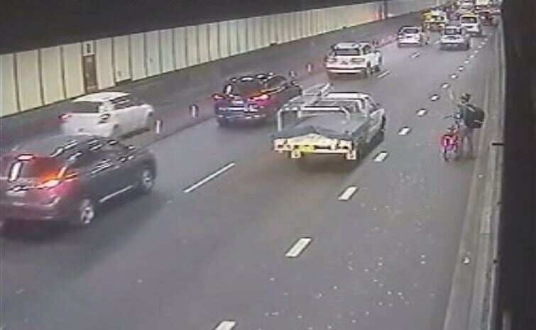A cyclist signals to a passing ute.