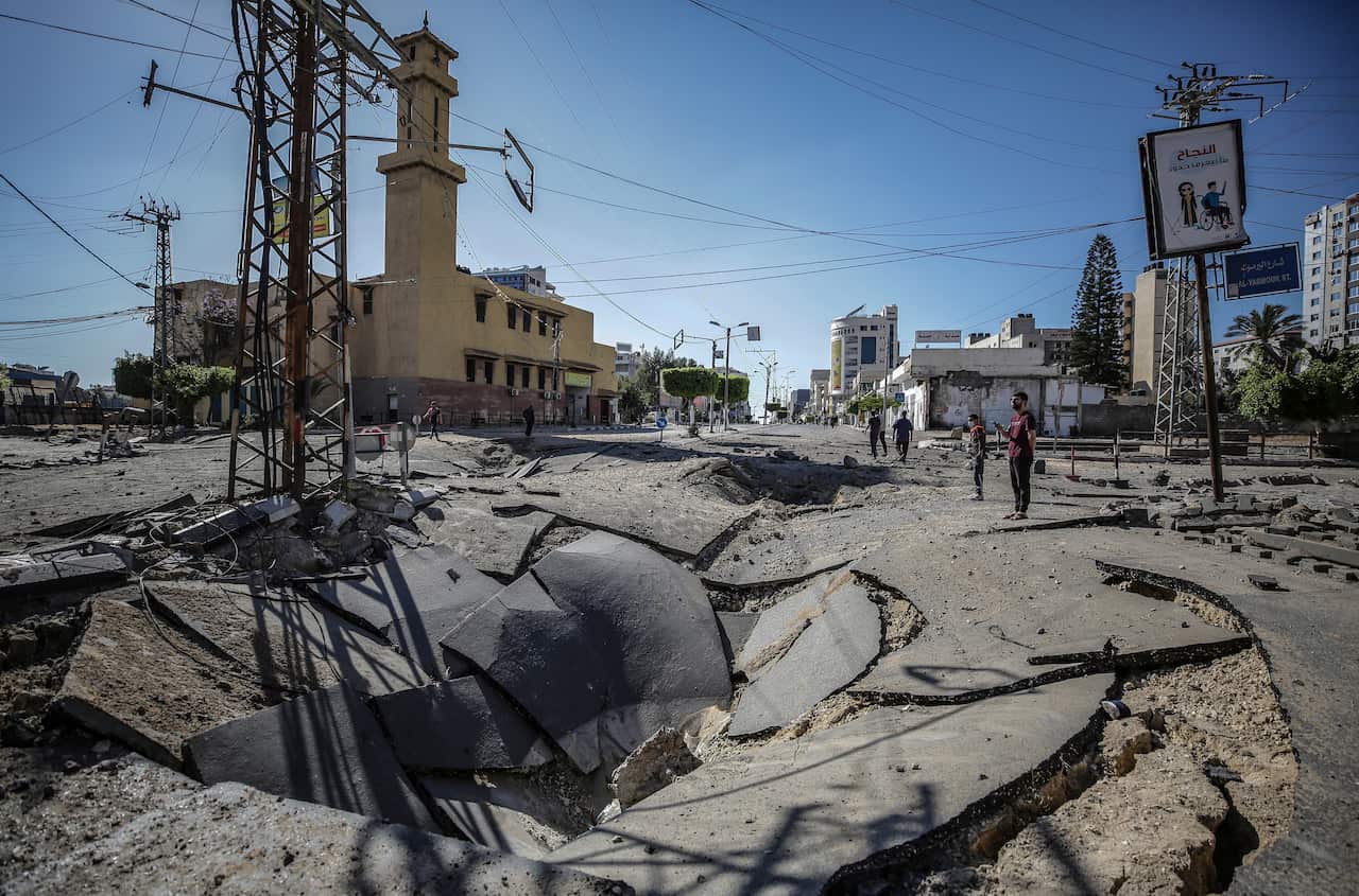 Palestinians inspect a destroyed street after an Israeli strike in Gaza City on 13 May 2021.