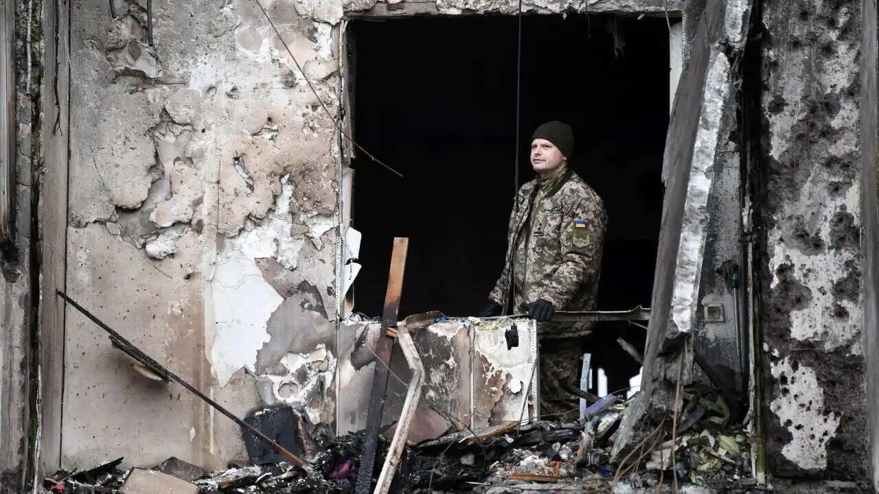 A Ukrainian serviceman is seen in the window of a damaged residential building in Kyiv.