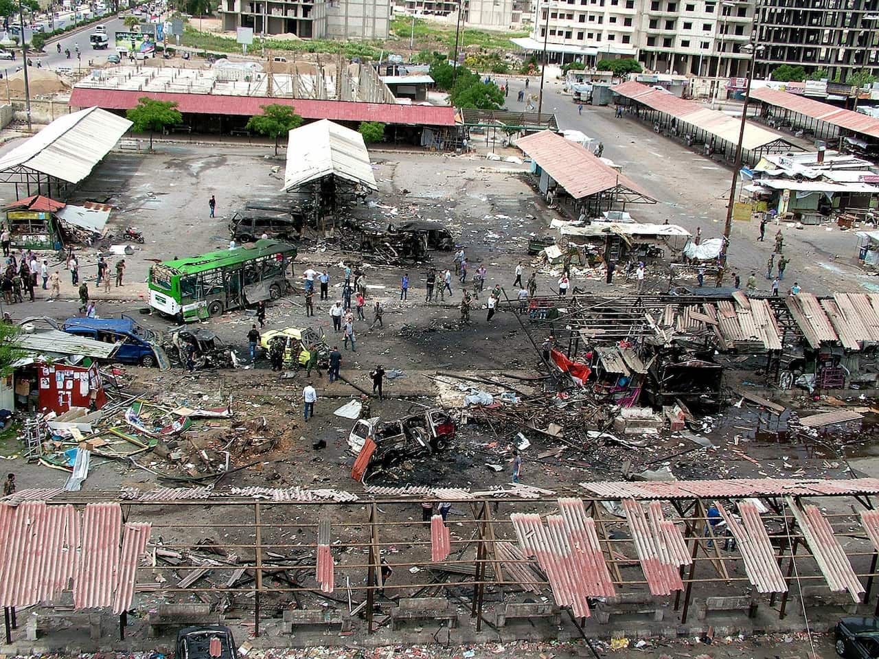  A photograph released by the official Syrian Arab News Agency (SANA) shows people inspecting the damage at the site of car bombing (AAP) 