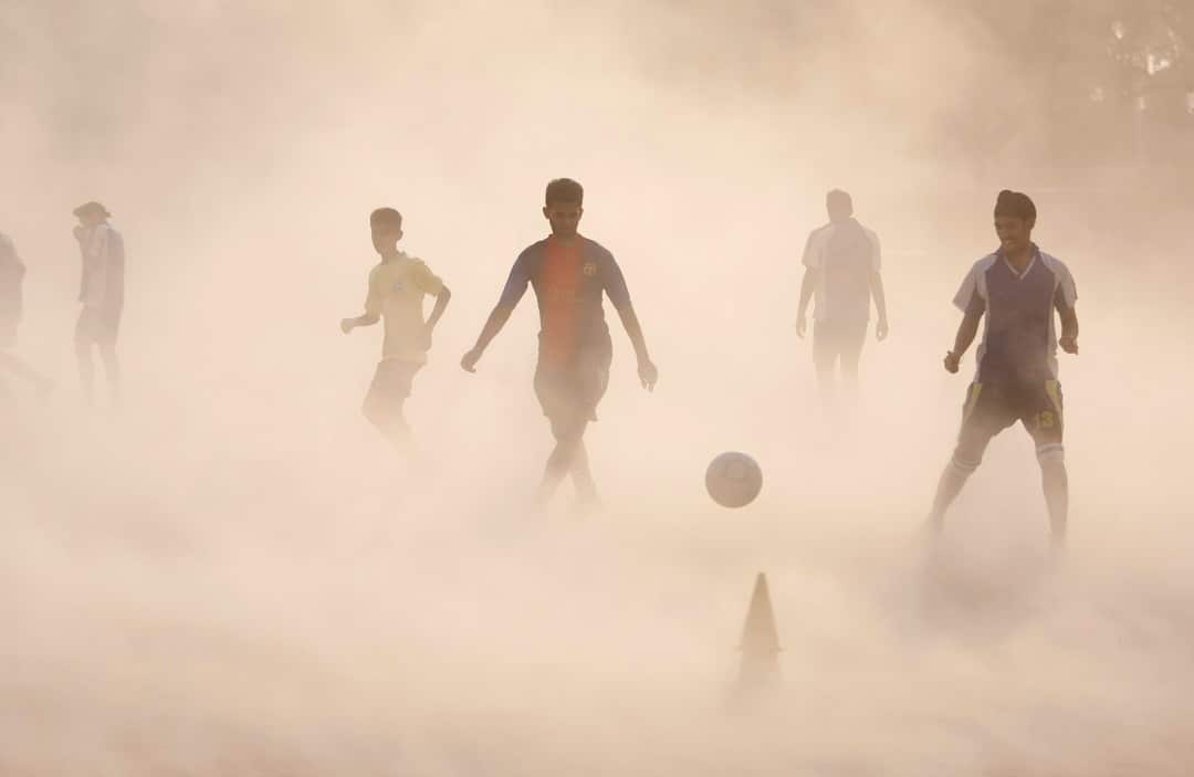 Aspiring young Indian soccer players continue with their practice during a dust storm in Jammu, India.