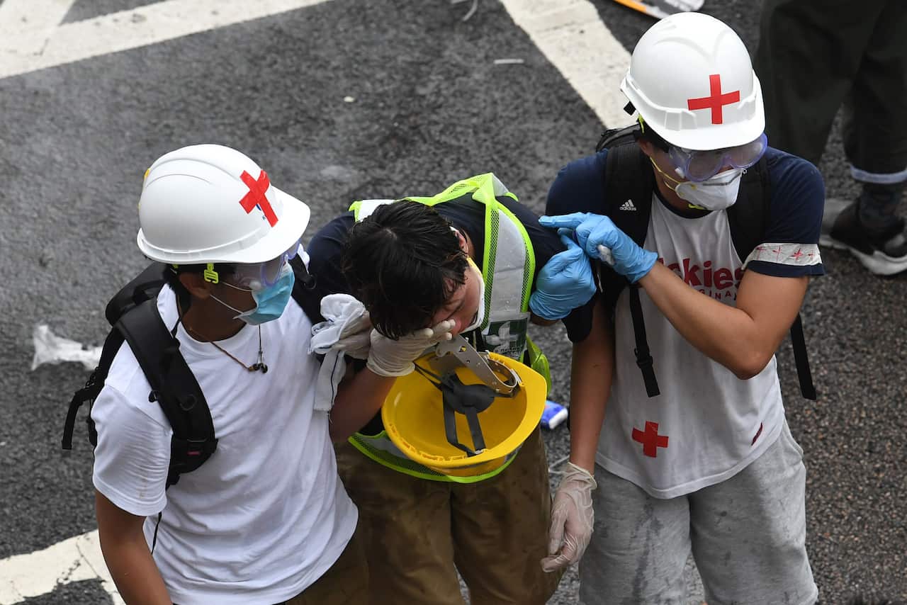TOPSHOT - A protester is helped by medical volunteers after being hit by tear gas fired by the police during a rally against a controversial extradition law proposal in Hong Kong on June 12, 2019. - Violent clashes broke out in Hong Kong on June 12 as pol