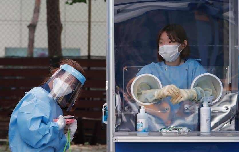 A medical worker holds a portable fan amid the sweltering heat during police officers the COVID-19 testing at a makeshift clinic in Seoul, South Korea.
