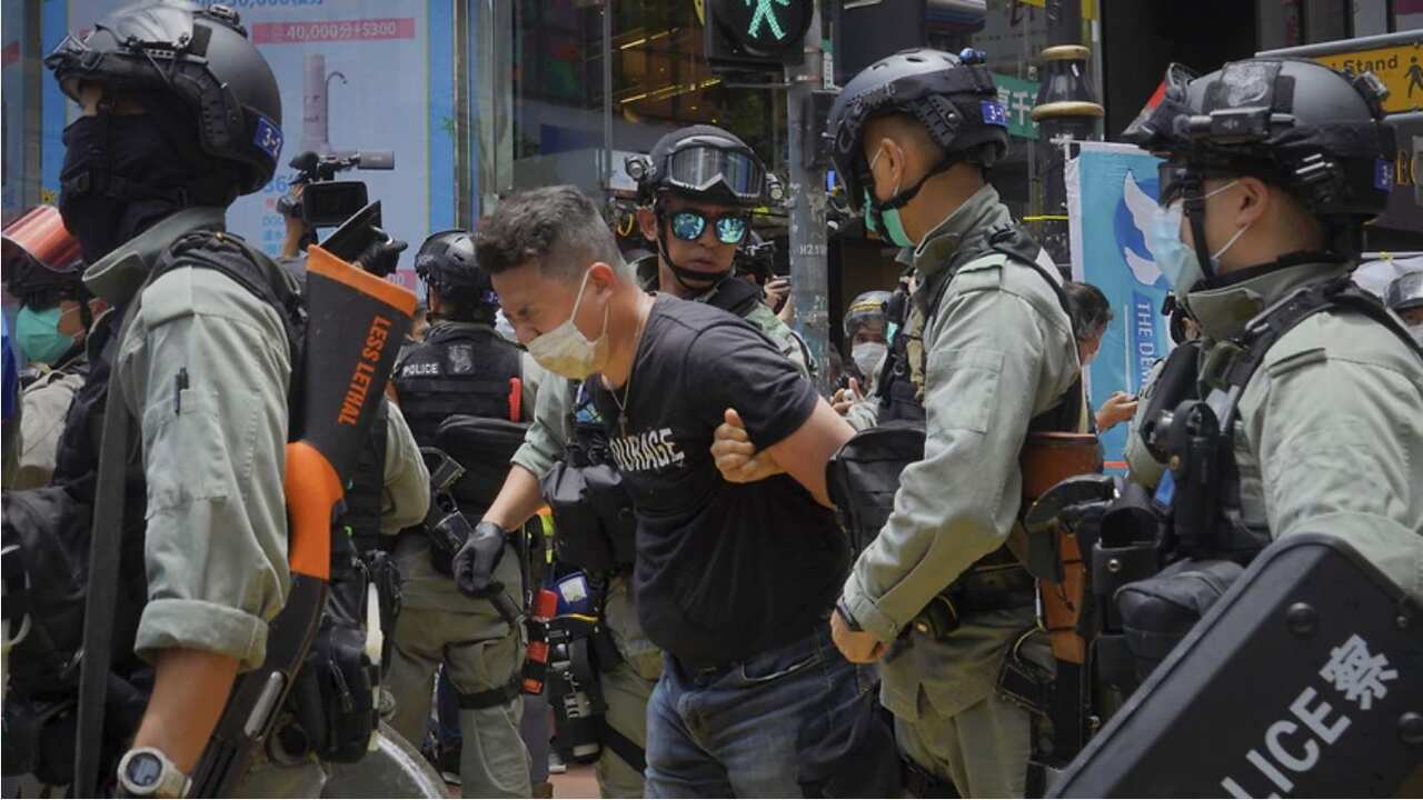 Police detain a protester after spraying pepper spray during a protest before the annual handover march in Hong Kong.