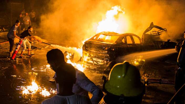 eople extinguish a fire from a blast inside the National Cancer Institute, Cairo, Egypt