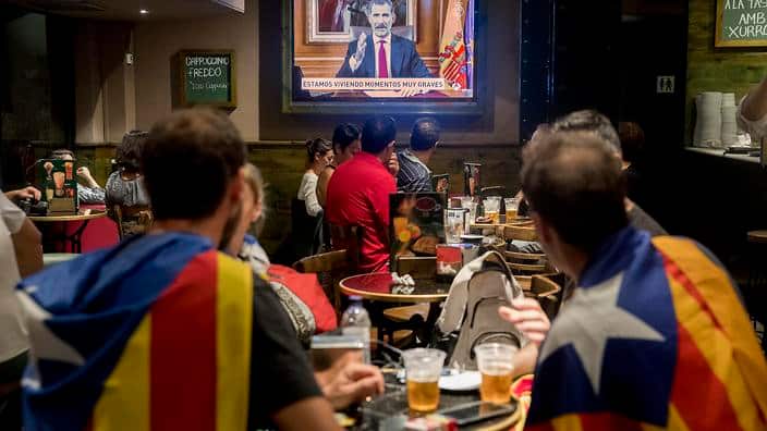 Catalan people, with the flag of the Republic of Catalunia on their shoulders, watch the King Felipe VI's televised address in a bar in Barcelona, Oct 3, 2017