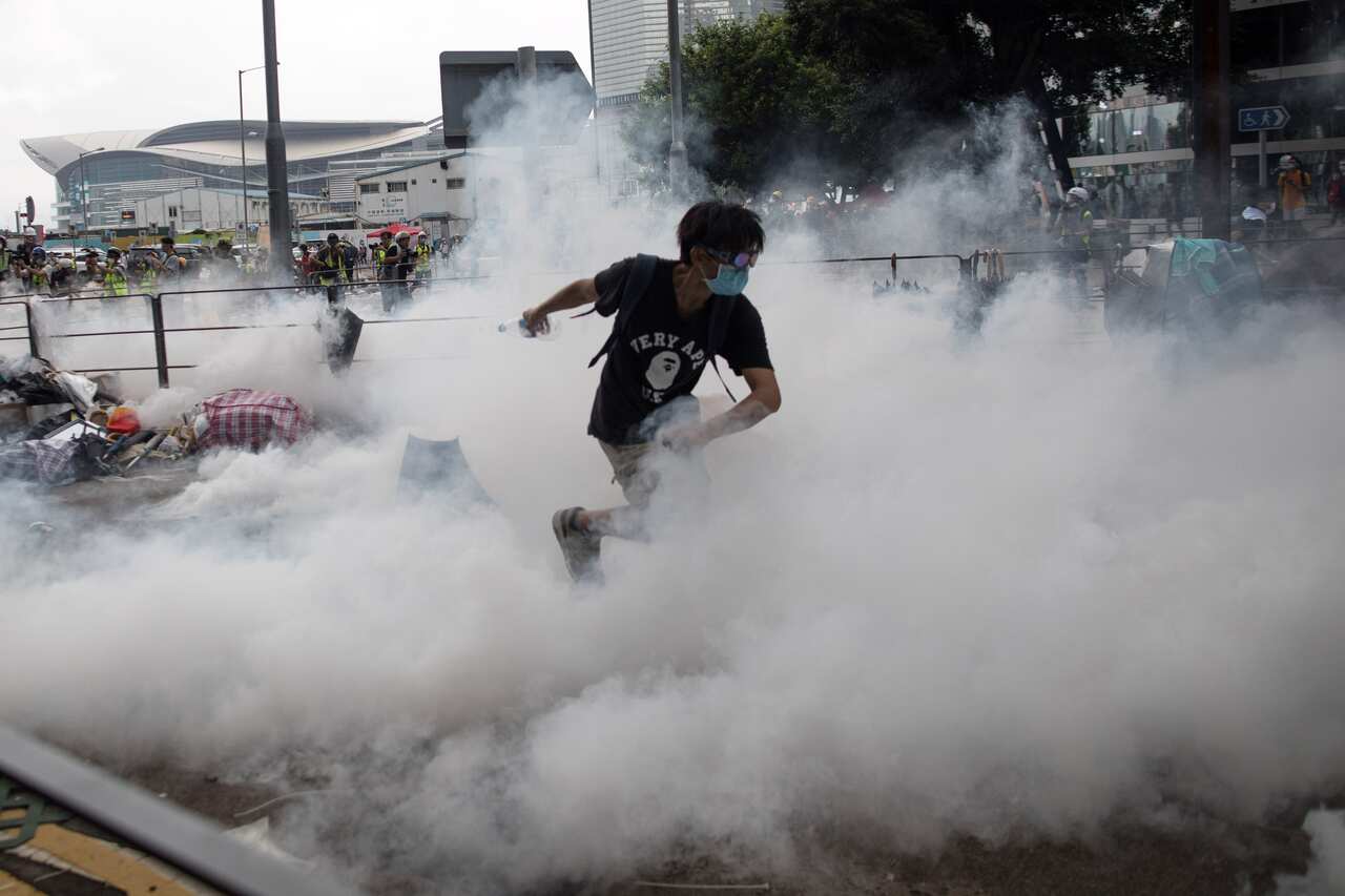 A protester runs away from tear gas shot by police during a rally against an extradition bill outside the Legislative Council in Hong Kong, China.