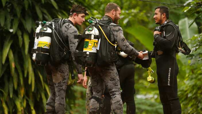 Australian Federal Police and Defense Force personnel talk to a Thai rescuer.