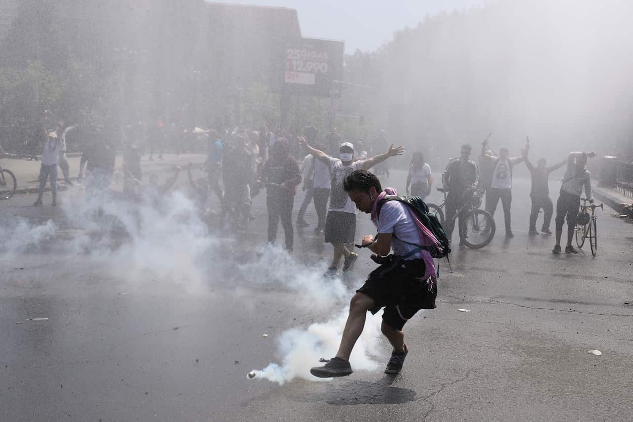 A protester kicks a tear gas canister during clashes with police in Santiago, Chile.