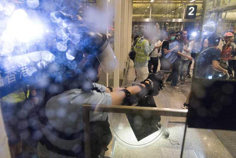 A police officer aims his gun against protesters during the Hong Kong airport demonstration.