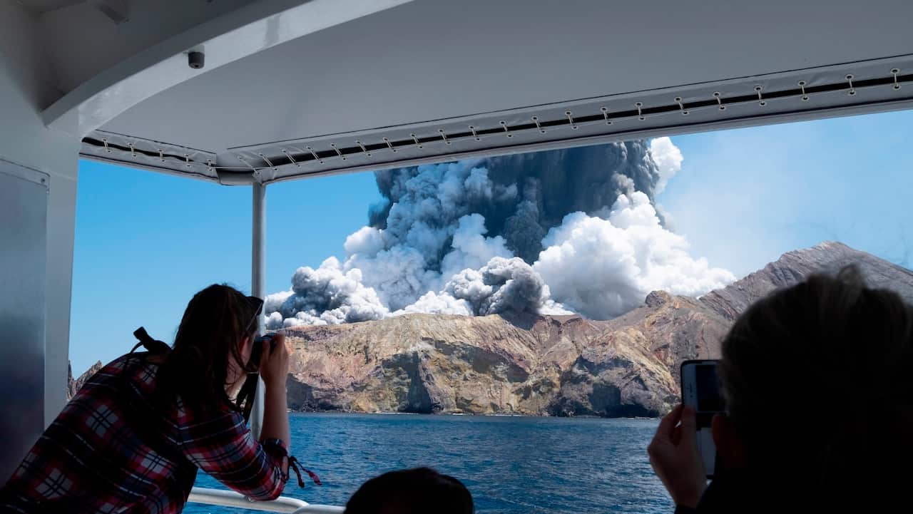 Tourists on a boat look at the eruption of the volcano on White Island.