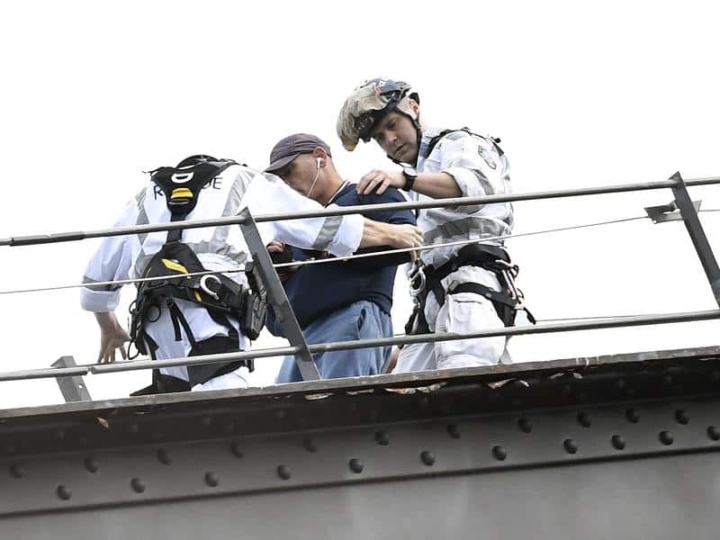 A man is escorted by police after climbing the Sydney Harbour Bridge
