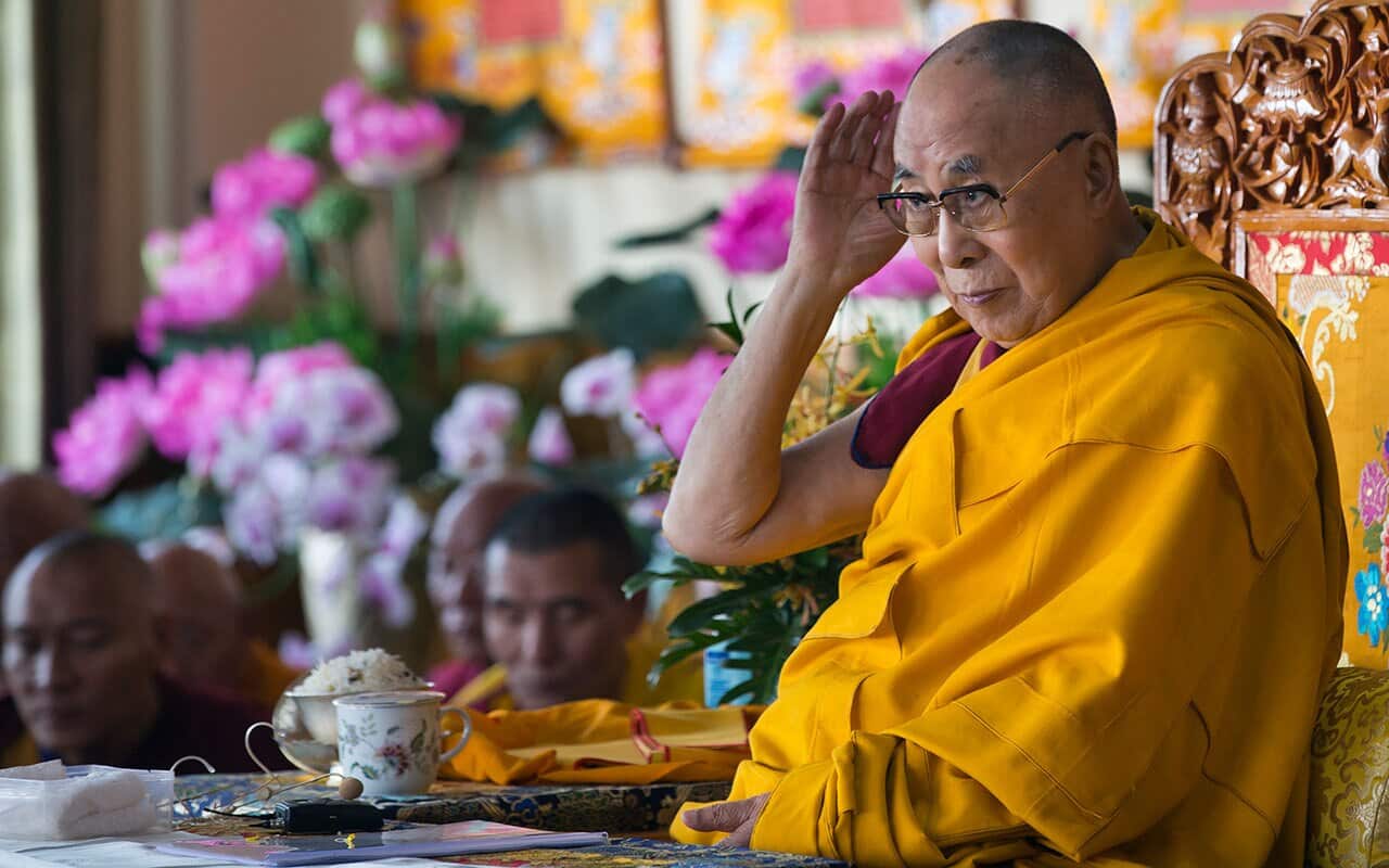 Tibetan spiritual leader the Dalai Lama cups his hand over his ear to listen to a debate as he presides over the inauguration of the Namgyal Monastery School.