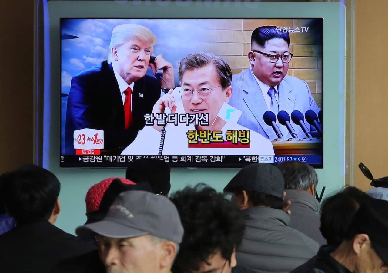 People watch a TV screen showing images of North Korean leader Kim Jong Un, right, South Korean President Moon Jae-in, center, and U.S. President Donald Trump