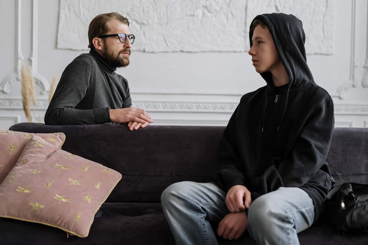 A boy sitting on a sofa with a counsellor