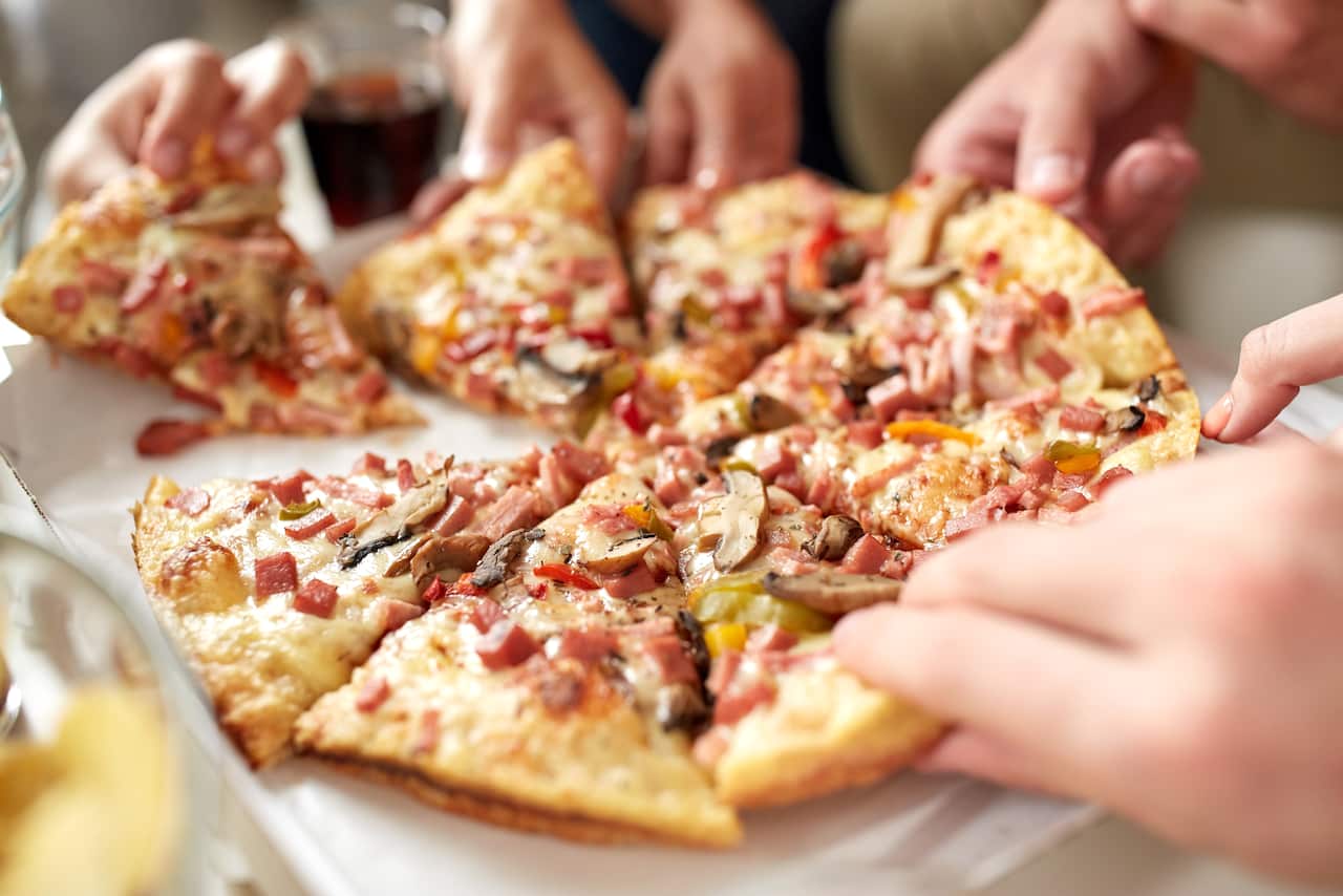 close up of hands taking pizza slices