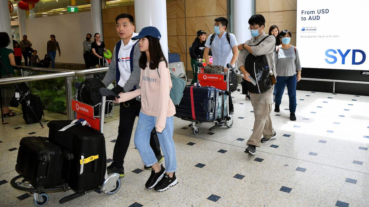Passengers wearing protective masks arrive at Sydney International Airport in Sydney, 23 January 2020.  