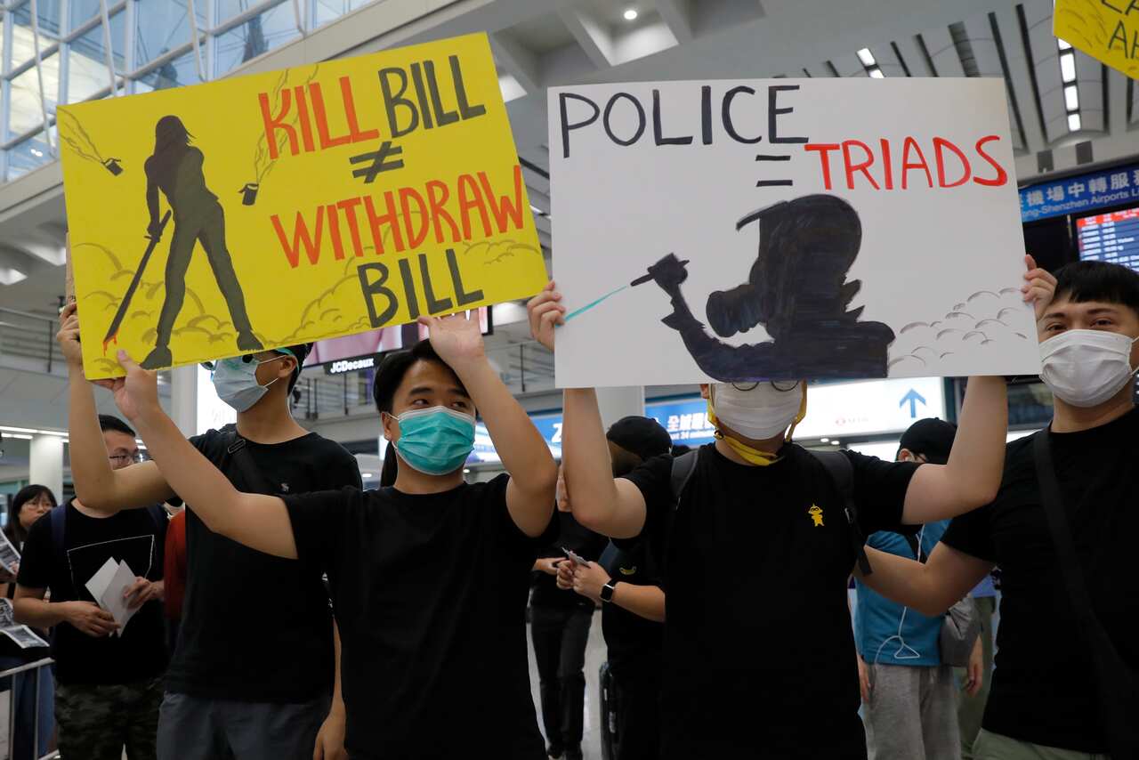 Demonstrators wave signs at travellers at Hong Kong airport.