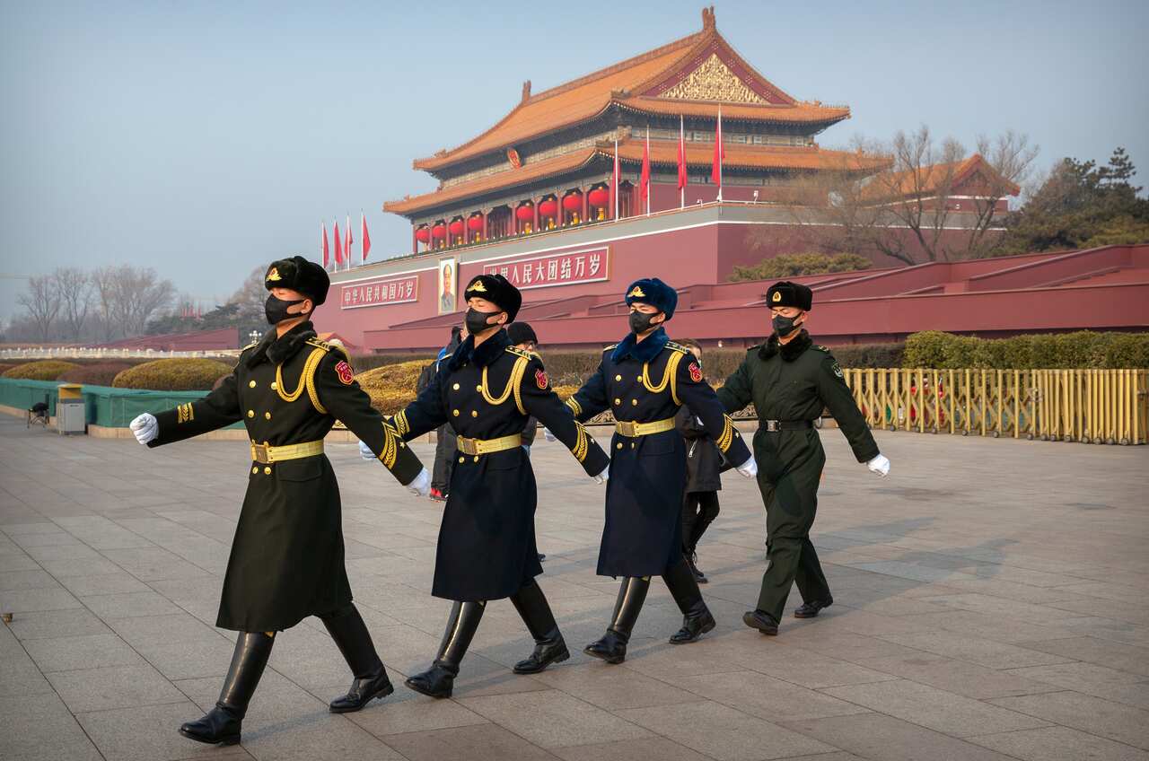 Security officials wear face masks as they march in formation near Tiananmen Gate adjacent to Tiananmen Square in Beijing, Monday, Jan. 27, 2020. China on Monday expanded sweeping efforts to contain a viral disease by postponing the end of this week's Lun