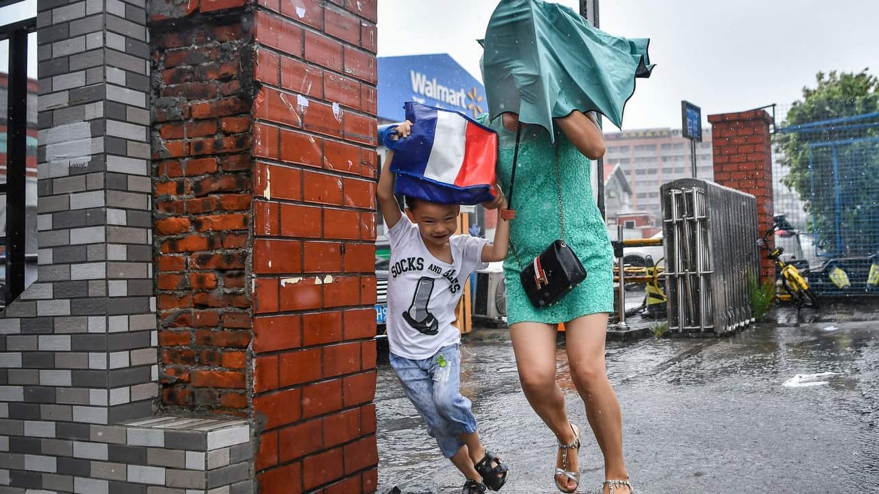 Pedestrians in Guangzhou city shield themselves with an umbrella against strong wind and heavy rain caused by Typhoon Mangkhut.
