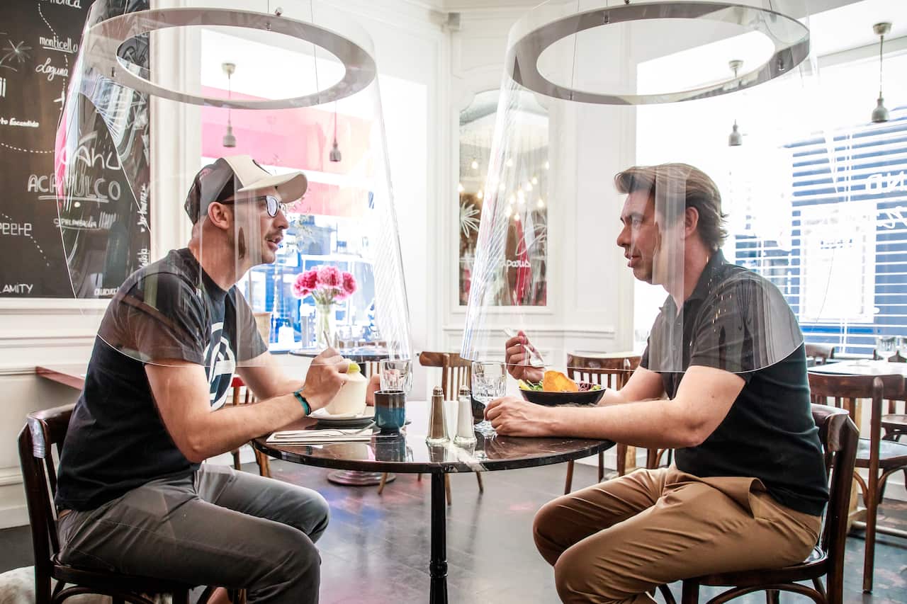 French Designer Christophe Gernigon (R) tries out his plexiglass bubble invention which surrounds customers to protect them from Covid-19 in Paris, France.