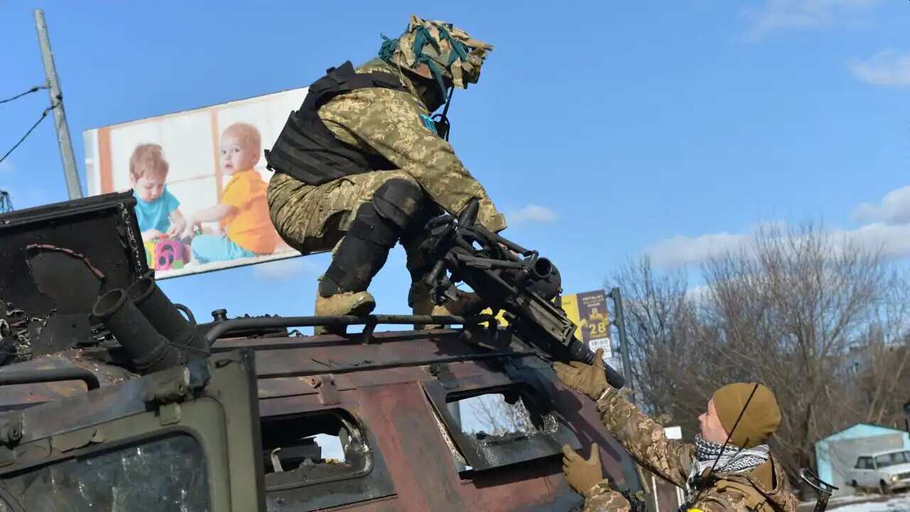 A Ukrainian Territorial Defence fighter takes the automatic grenade launcher from a destroyed Russian infantry mobility vehicle after a battle in Kharkiv on 27 February, 2022.