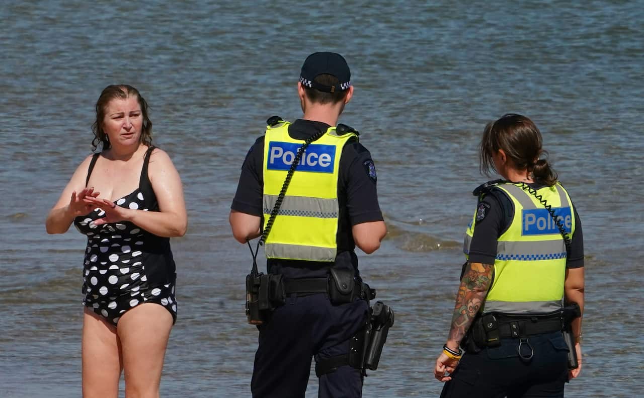 Police officers inform beachgoers that the beach is closed.