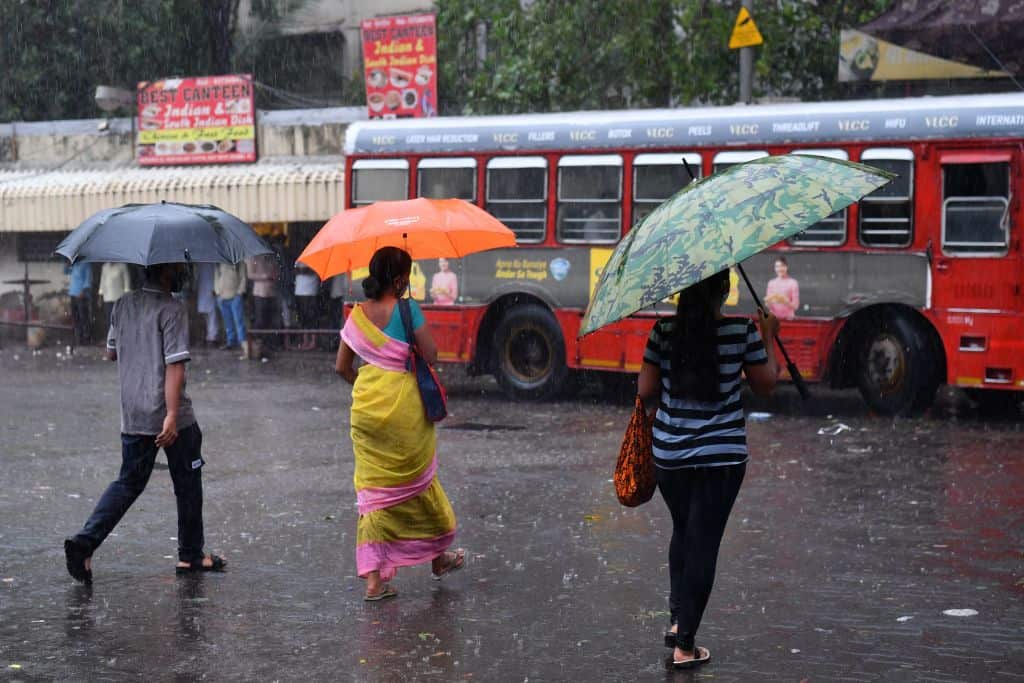 Passengers walk through a street near a bus terminus amidst heavy rains from Cyclone Tauktae in Mumbai on 17 May 17 2021.