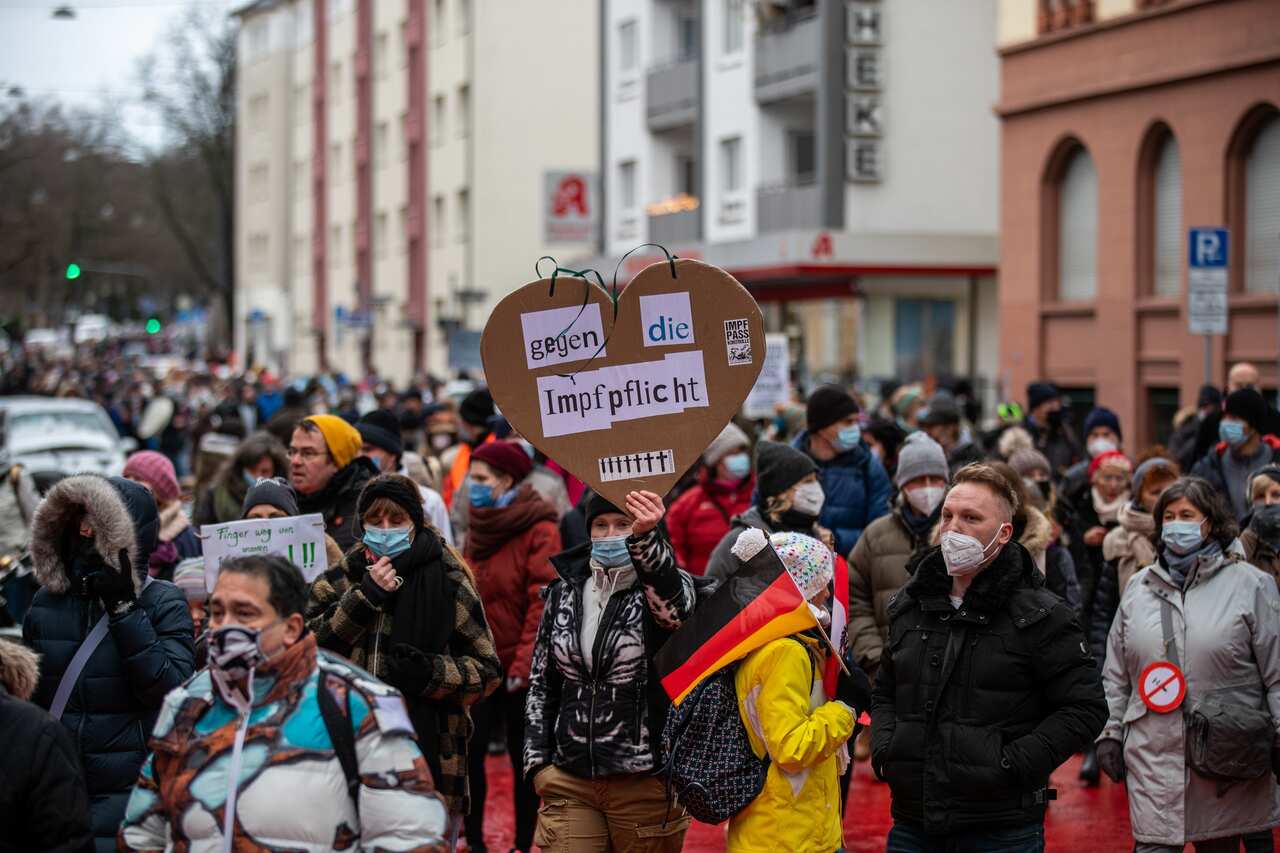 A supporter of the lateral thinking movement holds a sign reading 'Against compulsory vaccination', during a protest against the new requirements and measures against the spread of covid-19 infections, in Frankfurt am Main, Germany, 08 January 2022. The n