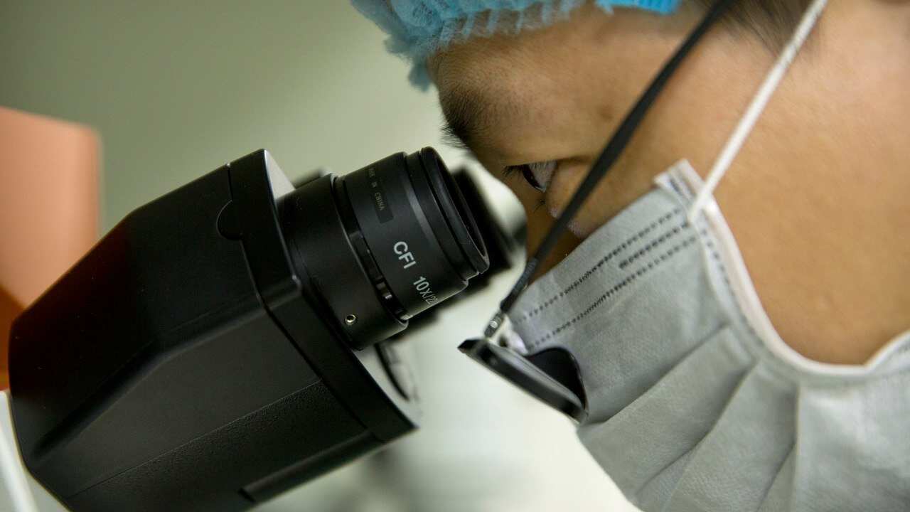 Scientist Qin Jinzhou looks through the lenses of a microscope in He Jiankui's lab in Guangdong, China.