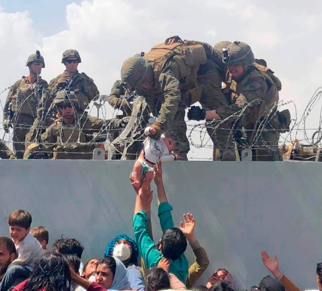 A baby being lifted across a wall at Kabul Airport in Afghanistan by US soldiers. 