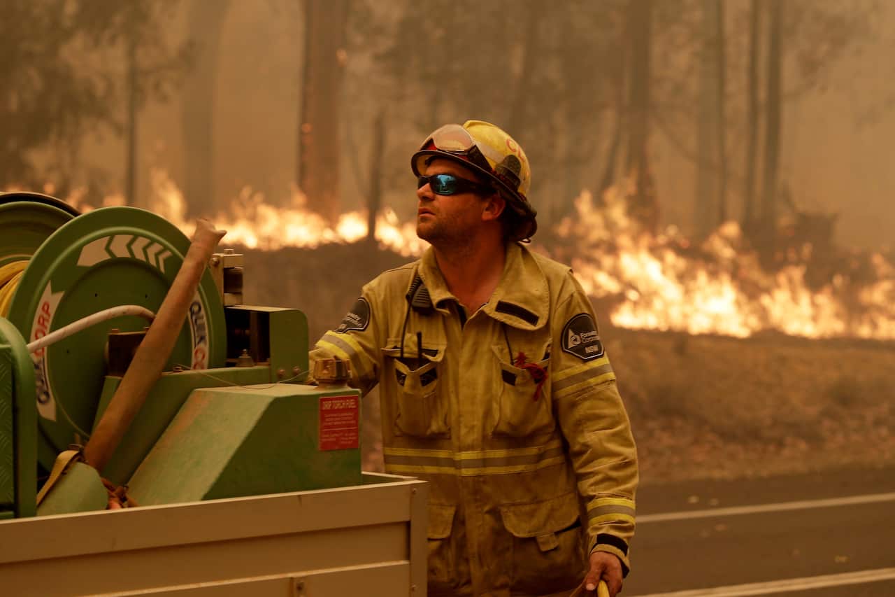 A Forest Corporation worker manages a fire hose as he battles a fire near Moruya, earlier this month.