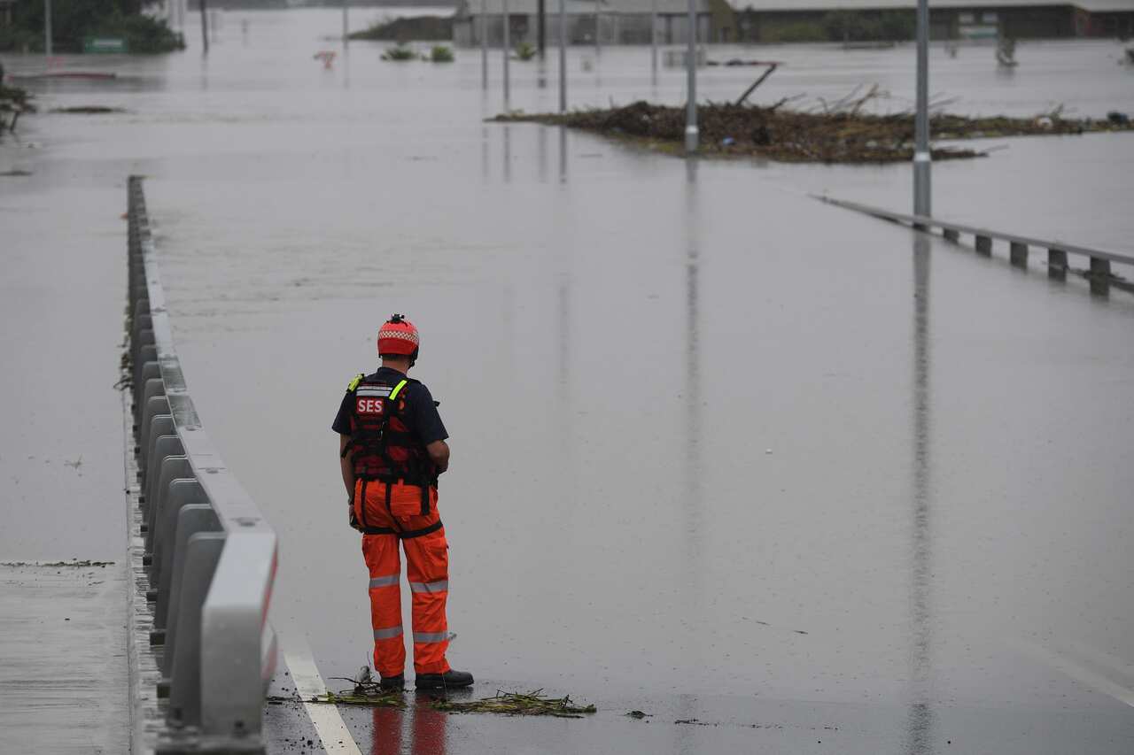 An SES flood rescue team member inspects floodwaters flowing over the New Windsor Bridge at Windsor in north western Sydney, Wednesday, March 23, 2021.