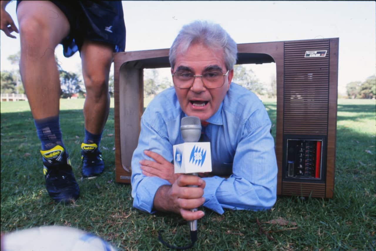 Les Murray with an SBS microphone, lying on grass