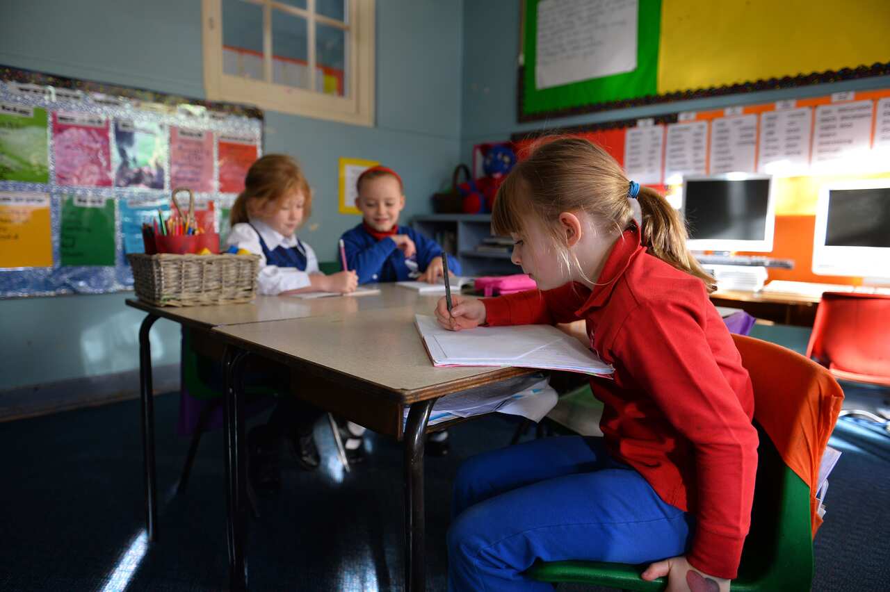 THIS IMAGE IS PART OF A PHOTO PACKAGE ON CHILDREN GOING TO SCHOOL AROUND THE WORLD6 years old student Frances McMillan (R) studies with classmates inside a classroom at school in the Coogee suburb of Sydney on June 17, 2013. AFP PHOTO / Saeed KHAN        