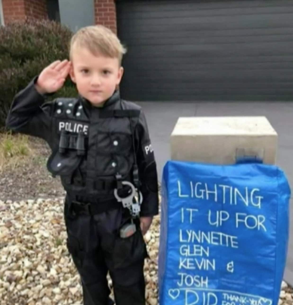 A Melbourne boy pays tribute to the four fallen officers in a police uniform outside his house.
