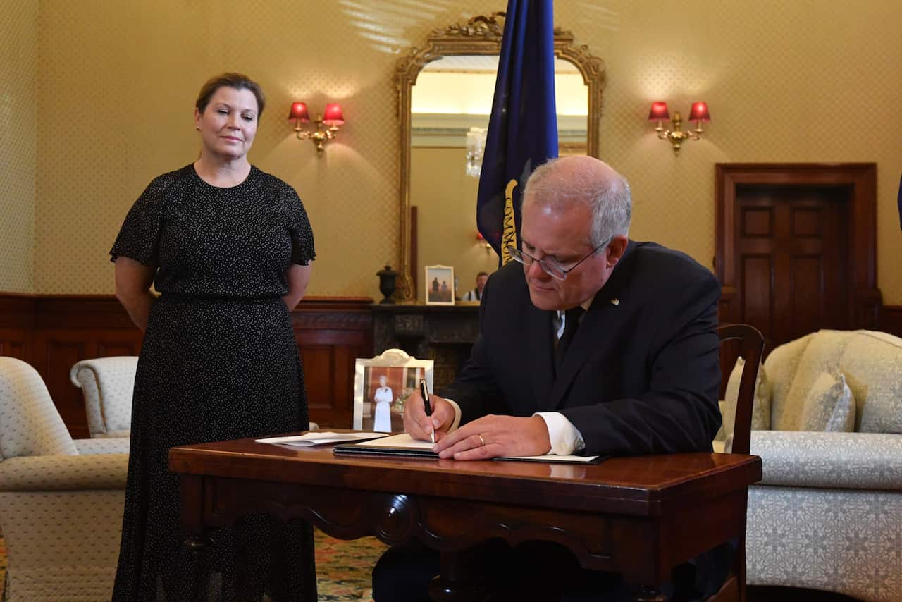 Prime Minister Scott Morrison signs a condolence book as wife Jenny looks on at Admiralty House following the death of Prince Philip, Duke of Edinburgh, in Sydney, Saturday, April 10, 2021. (AAP Image/Mick Tsikas) NO ARCHIVING