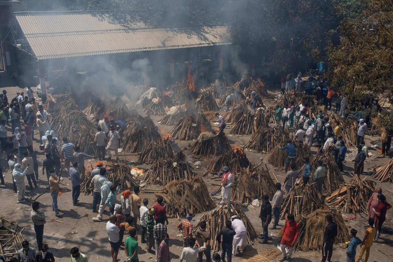 Multiple funeral pyres of those who died of COVID-19 burn at a ground that has been converted into a crematorium.