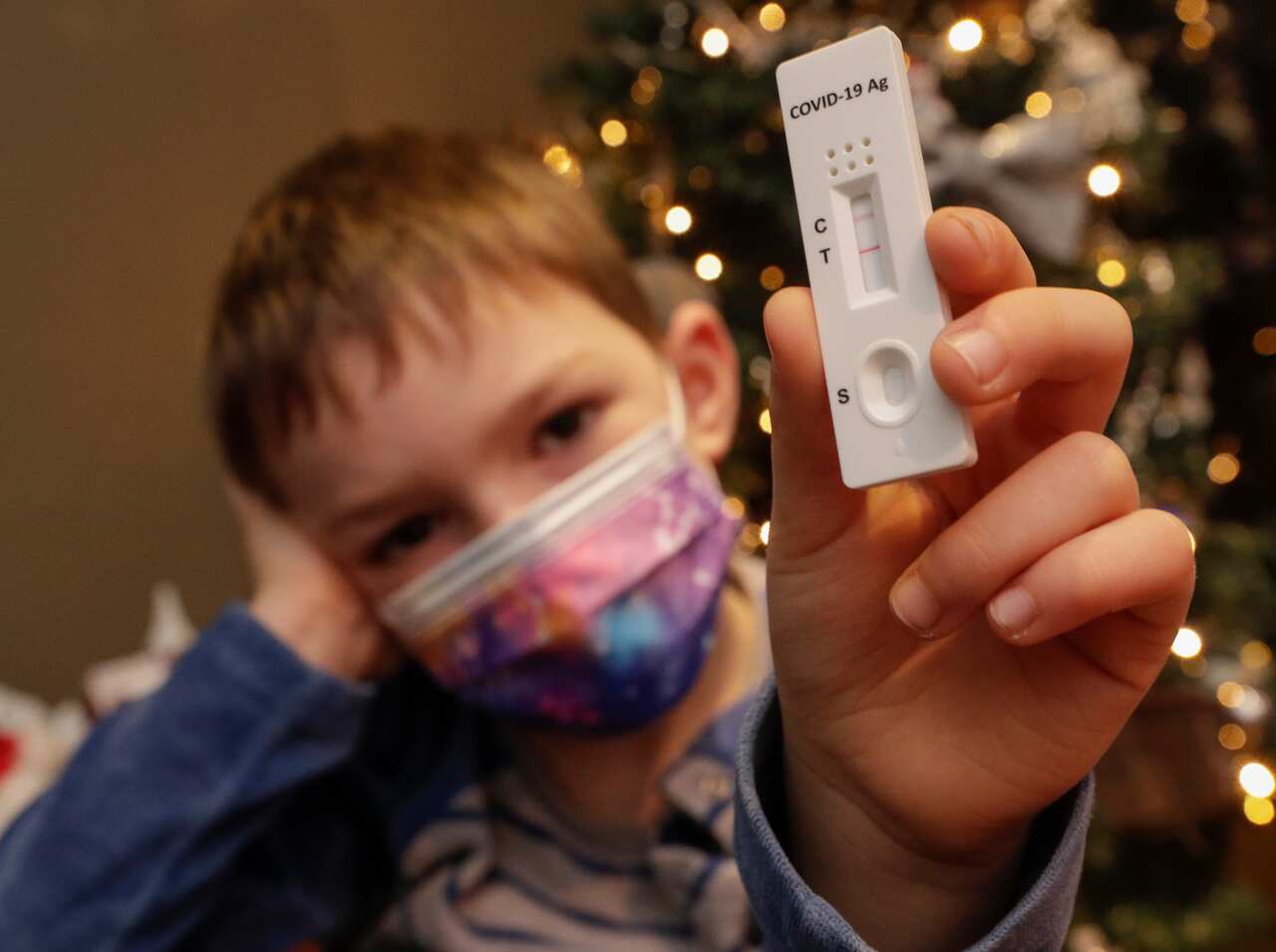 A Child poses with a positive rapid Covid-19 Antigen test
