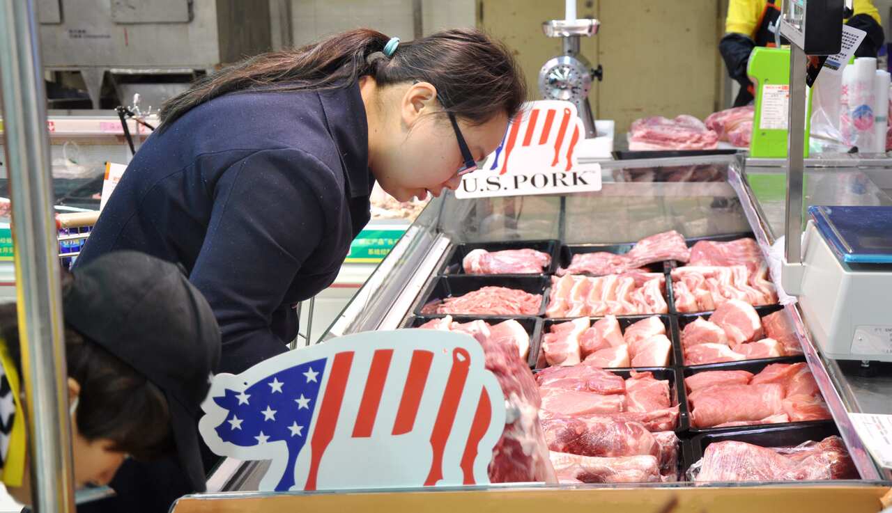A customer buys pork imported from US at a supermarket in Zhengzhou city, central China's Henan province
