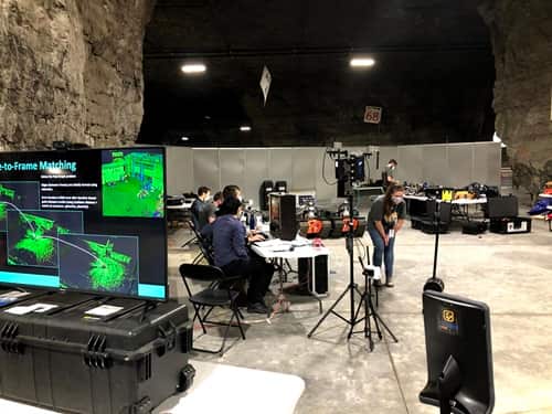 A shot of team CSIRO's Data61's work area, with a team member talking. to another based in Australia via telepresence robot.