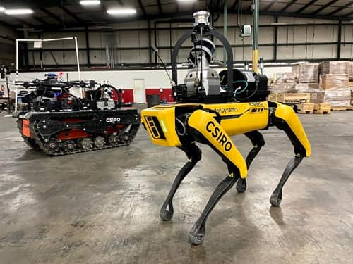 One of team CSIRO's Data61's quadruped robots in the foreground with one of the tracked all terrain robots carrying an aerial robot in the background.