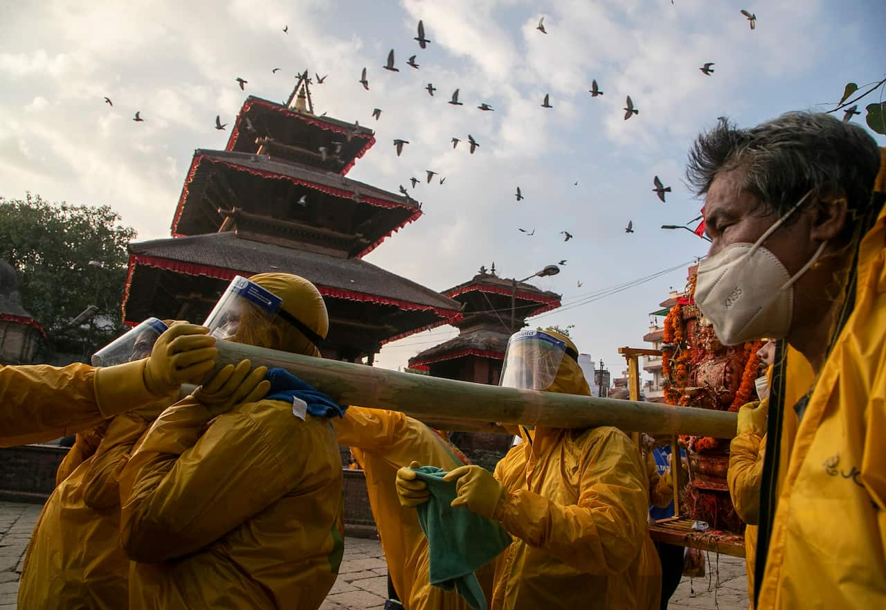 Nepalese devotees wearing protective gear as a precautionary measure against the coronavirus carry the chariot during Pachali Bhairav festival in Kathmandu, Nepal, Wednesday, Oct. 21, 2020.